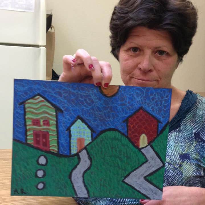 Woman with special needs holding up artwork